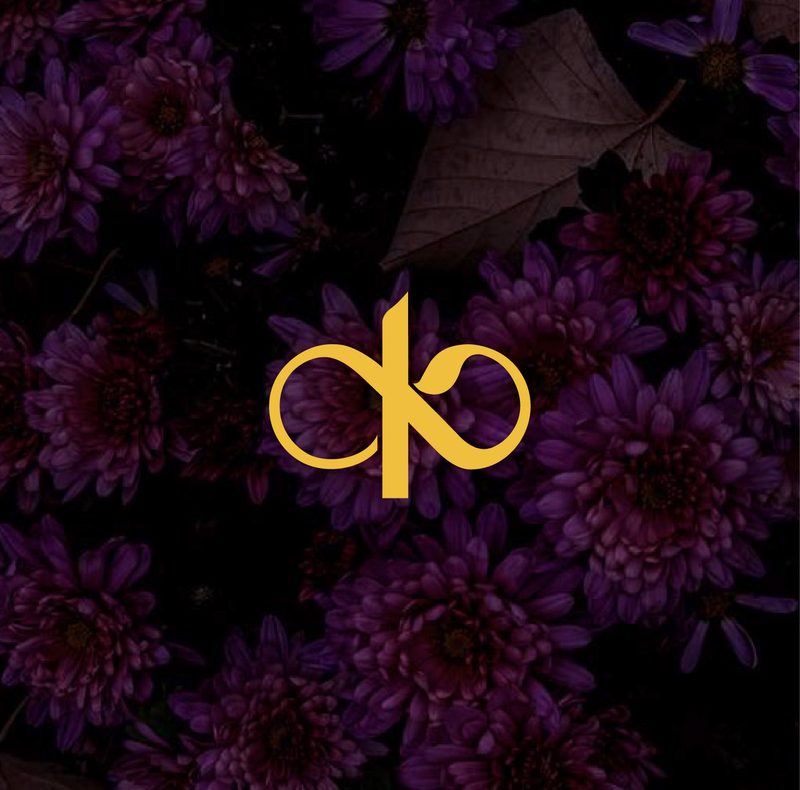 Kanakvira icon mark in Golden Yellow on a deep plum floral background